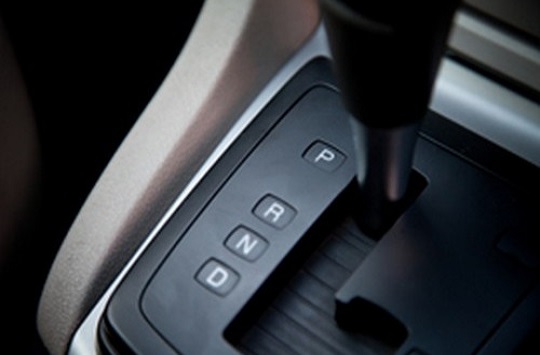 image of an automatic transmission gear stick inside of a vehicle, with gear in 'P' mode. Other modes shown are 'R' (for Reverse), 'N' (for Neutral) and 'D' (for Drive).